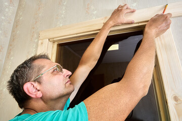 Obraz premium Installing door frame, marking casing using pencil.