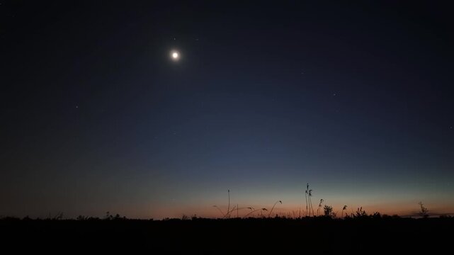 Hyper lapse of stars, Moon, moving airplanes with a dark landscape.