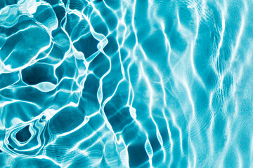 Sunlight creates rippling patterns on surface of clear blue water, highlighting beauty and movement. Water background. Selective focus, defocus