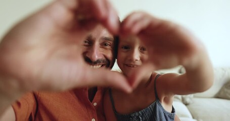 Cheerful middle aged Latin dad and cute little daughter kid lifting hand heart shape gesture at camera, joining fingers in symbol of love, family care, childcare, smiling for portrait