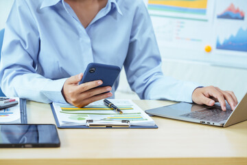 A young Asian woman sits at a desk, attentively analyzing graphs and financial data. She is focused and determined, highlighting her expertise in financial analysis and business strategy.