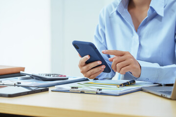 A young Asian woman sits at a desk, attentively analyzing graphs and financial data. She is focused and determined, highlighting her expertise in financial analysis and business strategy.