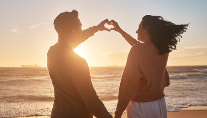 Couple, sunset and love sign at beach with hands for date, relationship and romantic moment...
