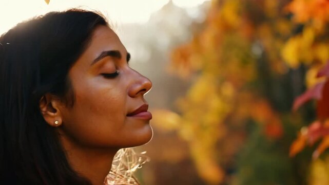 Young woman meditating in autumn forest. Orange fall season and sunlight. Young cheerful woman makes a deep breath and enjoy the fresh air while walking in the misty forest on a fall day. Beauty