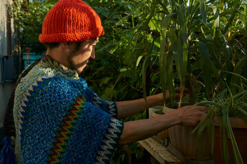 man in a poncho looks at a plant