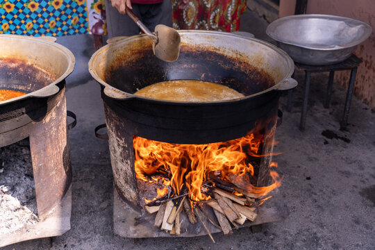 A person is cooking food in a large pot over a fire