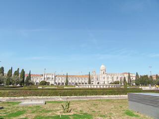 Historic European monastery with manicured gardens under blue sky