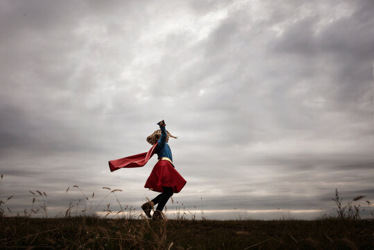 Young girl twirling in cape and super hero costume