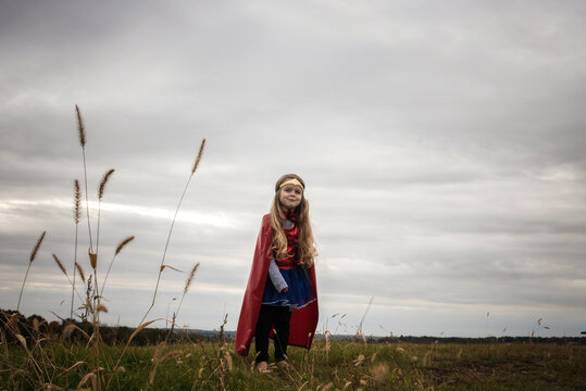 Happy little girl wearing red cape superhero