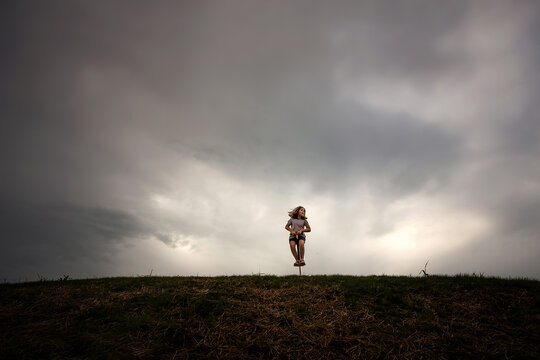 Young girl bouncing on pogo stick outdoors