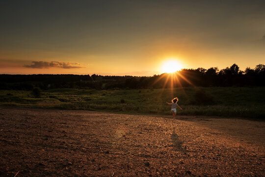 Young girl running towards golden sunset