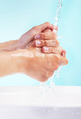 Person, water and washing of hands in studio for bacteria, hygiene and germ protection in basin. Cleaning, skin hydration and body care with liquid for disinfectant or virus safety on blue background