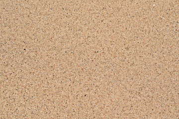 Sun shines to wet sand on beach, closeup detail from above