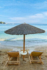 Sunbeds and umbrella on the sandy beach on Crete. Scenic landscape of Mediterranean sea in Greece.