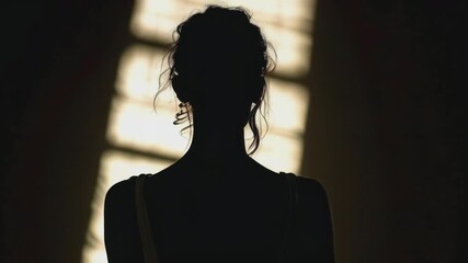 Silhouette of a woman with elegant hairstyle standing against a bright, ethereal light background. Ideal for themes of mystery, anonymity, beauty, and artistic expression