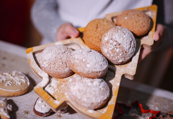 Hands hold cookies on a plate in the shape of a Christmas tree.