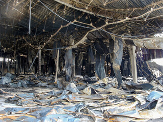 Aftermath of a fire at a construction site, showing extensive damage to the structure and materials