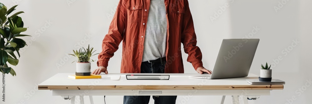 Poster man standing at a desk with a laptop in a minimalist office. promoting an inclusive work environment