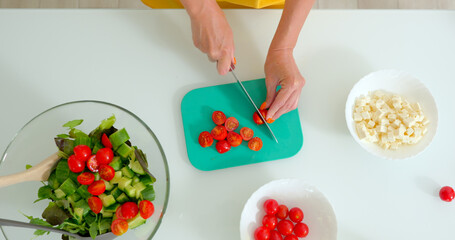 Woman slices tomatoes for a vegetable salad