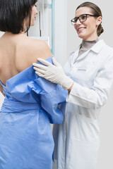 A woman doctor close-up stands against the background of a patient who is doing a mammogram. early...