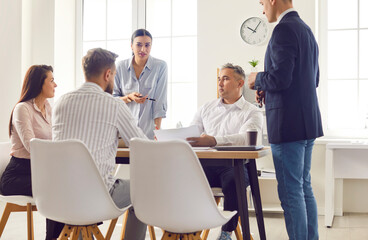 Positive team of business people holding a work meeting or negotiations with colleagues in an office. Collaboration, partnership, and professional teamwork in the business environment.