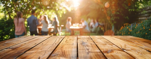 Empty wooden table and blurred view of a group of people having BBQ barbecue outdoors. Wood desk in front of a natural garden background. Summer lifestyle concept.