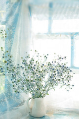 A bouquet of dried flowers in a ceramic jug on an old wooden window in a country house.