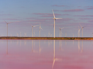 Fototapeta premium Wind Turbines Reflected in Pink Salt Lake at Sunset