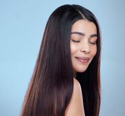 Naklejka premium Woman, happy and hair care in studio with beauty for luxury salon treatment, shampoo or cosmetic. Girl, smile and healthy texture, transformation and growth for hairdresser results on blue background