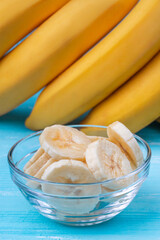 A banch of bananas and a sliced banana in a pot over a table.