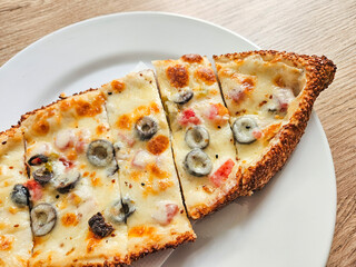 Delicious Turkish sesame bagel pizza made of cheddar cheese, tomato and olives on a table. Snack or breakfast concept.