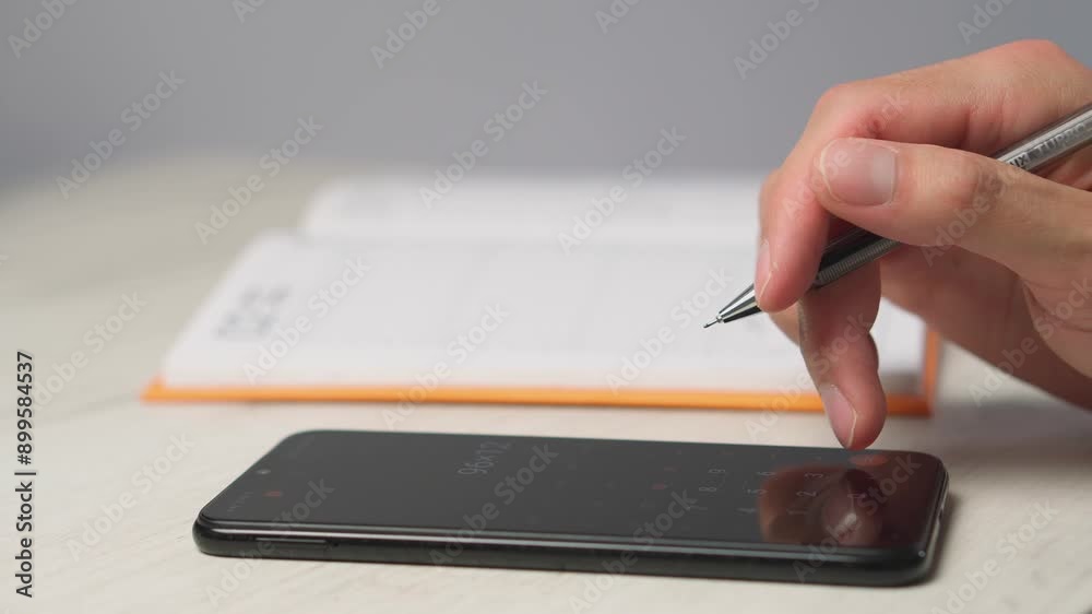 Aufkleber A person skillfully combines technology with traditional notetaking, writing in a notebook next to a smartphone on a desk. This blend of tools enhances organization and productivity
