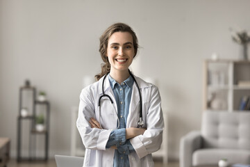 Successful medical worker portrait. Young female intern wear white coat posing with arms-crossed at...