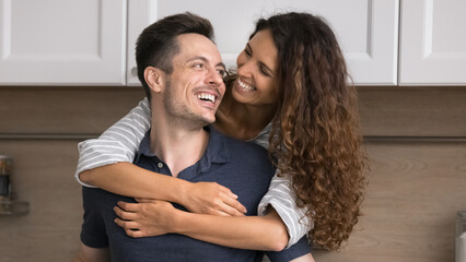 Fototapeta premium Loving Hispanic spouses spend time together in renovated modern kitchen, loving wife snuggle tightly husband, expressing love and affection. Bank loan, tenancy, romantic relationships, happy marriage