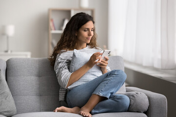 Obraz premium Hispanic woman using modern smartphone spend free time on internet, scroll news feed, enjoy new mobile application, chatting on-line, communicates remotely, making personal call, order goods at home