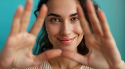 Fototapeta premium Portrait of cheerful smiling young woman raising her hand and putting it in front of her face.