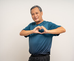 Senior asian old man with sportswear showing heart sign on isolated white background. Portrait happy healthy fit and firm attractive sporty mature man standing pose exercise workout in studio.