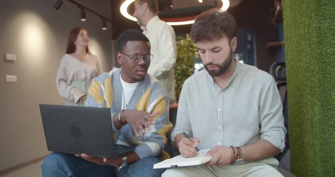 Experienced workers discussing business strategies and market research in a modern co-work space. Focused on stock market analysis and new opportunities for profit.