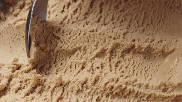 Slow motion closeup hazelnut praline ice cream scooping with spoon