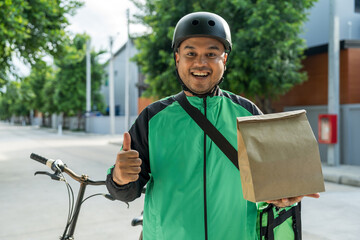 Portrait Rider food delivery man wearing green uniform and helmet cycling a bicycle the food service to customer. Happy delivery man with green backpack shipping of goods to customers.