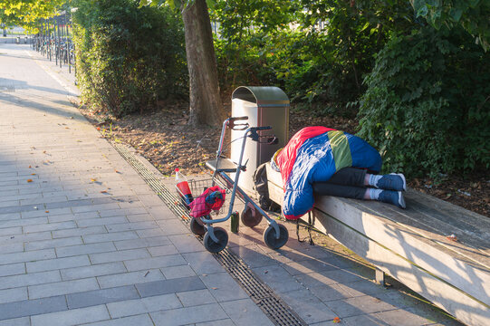 Ein Obdachloser schl&auml;ft auf einer Parkbank , davor sein Rollator