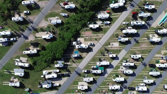 Long concrete pads and full power hook-ups with parked recreational vehicles in premium RV park in South Padre Island beach, Texas, tall palm trees, modern basecamp with picnic tables, fire rings