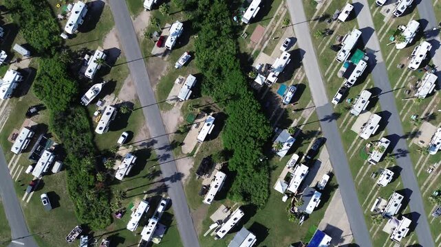 Straight flyover view long row of RV campers with travel trailers, cars, boats in premium RV sites with concrete pads, full hook-ups in South Padre Island beach, Texas, recreational vehicles park
