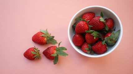Red fresh strawberry in white bowl isolated on pink background
