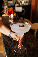 Margarita cocktail with salt, tequila, lime, girl holding the glass in a bar 