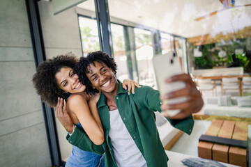 Portrait of a young cheerful couple of African descent standing in a modern luxury villa, taking a...