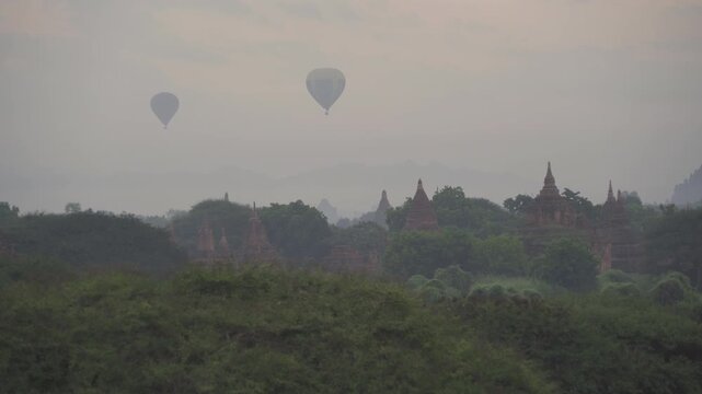 Balloons flying over Burmese temples of Bagan City from a balloon, unesco world heritage with forest trees, Myanmar or Burma. Tourist destination.