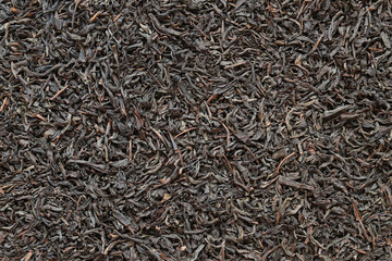 Long black tea, texture. Top view of dried tea leaves. Tea composition. Ingredients for a hot drink, close-up. Background