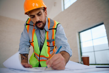 Male worker drawing housing plans at construction site.