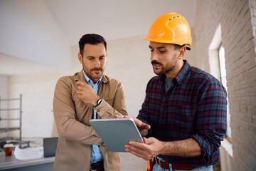 Building contractor and home owner using touchpad at construction site.